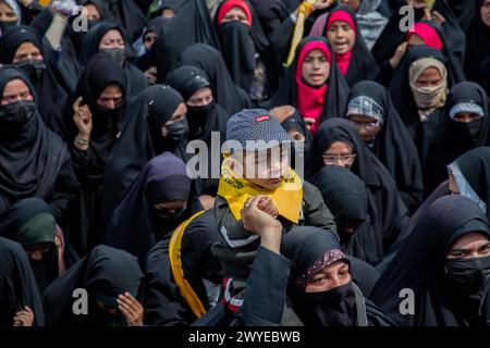 Srinagar, Indien. April 2024. Eine muslimische Frau hält ihr Kind über der Menge, während sie während eines Protests gegen Israels Militäroperationen in Gaza Slogans gegen Israel und Amerika singt. Dutzende Kaschmirmuslime trugen Plakate und palästinensische Flaggen während einer Kundgebung im zentralen Kaschmir-Magam, etwa 25 km von Srinagar entfernt, zum Gedenken an den Al-Quds-Tag (Jerusalem). Der Al-Quds-Tag wird weltweit am letzten Freitag (Jumat-ul-Vida) des Heiligen Monats Ramadan begangen, um Solidarität und Unterstützung für die Palästinenser zum Ausdruck zu bringen. Quelle: SOPA Images Limited/Alamy Live News Stockfoto