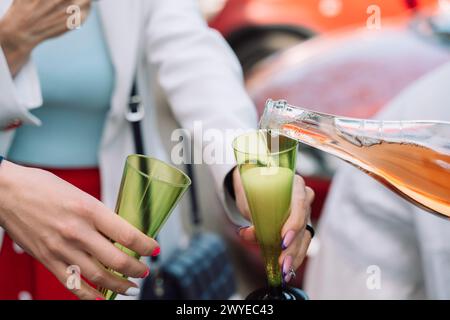 Eine Frau gießt Wein in zwei grüne Gläser. Die Gläser sind mit Wein gefüllt und die Frau hält sie an den Mund. Die Szene spielt in A Stockfoto