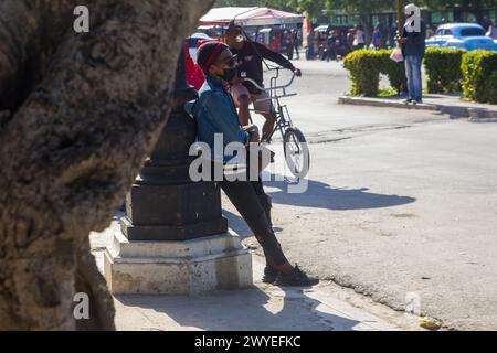 Eine kubanische Person, die sich an eine alte Straßenlaterne im Stadtzentrum von Havanna, Kuba, lehnt Stockfoto