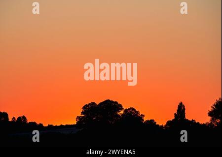 Ein dramatischer orangefarbener Sonnenuntergang über Perry Moor in der Nähe von Muchelney, Somerset, England, an einem klaren Sommerabend. Stockfoto