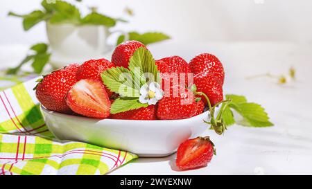 Erdbeeren in weißer Porzellanschüssel auf einem Tisch. Schüssel gefüllt mit saftig frischen reifen roten Erdbeeren. Selektiver Fokus Stockfoto
