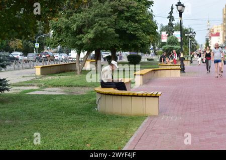 Ein Mann ruht sich auf einer Bank aus und liest ein Buch. Stockfoto