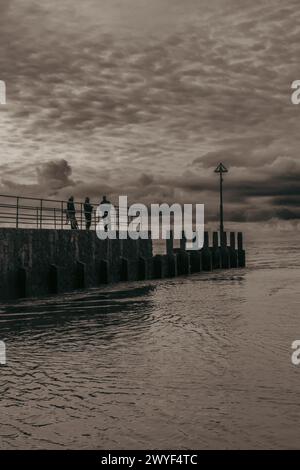 Silhouette von Leuten, die auf dem Groyne stehen Stockfoto