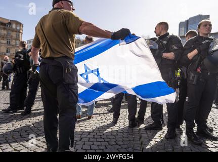 06. April 2024, Hessen, Frankfurt/Main: Ein Gegendemonstrator hält während einer Demonstration zum Al-Kuds-Tag in der Frankfurter Innenstadt eine israelische Flagge. Foto: Frank Rumpenhorst/dpa Stockfoto