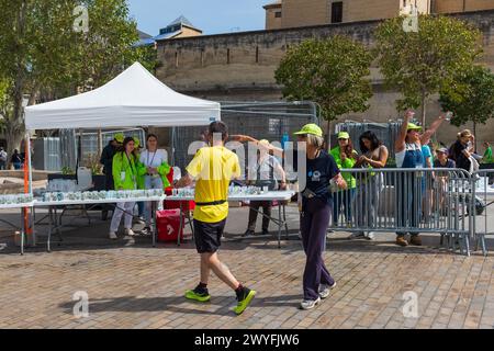 Montpellier, Frankreich. April 2024. Freiwillige Helfer helfen Läufern an einer nachhaltigen Wasserstation mit wiederverwendbaren Gläsern beim Staffelrennen Ekiden beim Montpellier Run Festival. Credit ReportageMPL/Alamy Live News Stockfoto