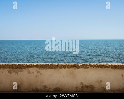 Leerer Blick auf den Horizont über eine Steinmauer am Ufer der Küstenpromenade von Cadiz auf der Avenue Campo del Sur während eines Sommerurlaubs, Blick aufs Meer, Stockfoto