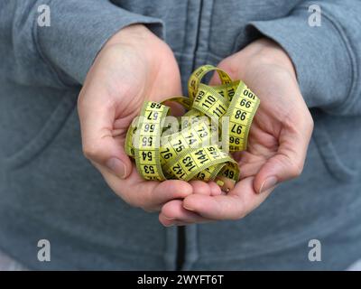 Eine Frau, die ein gelbes Maßband in den Händen hält. Nahaufnahme. Stockfoto