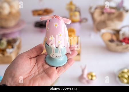 Eine Hand hält ein Osterei in einem sehr süßen und lustigen Osterhasen-förmigen Behälter. Stockfoto