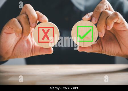 Symbolisch mit Ja oder Nein, hält die Hand Holzwürfel mit einem grünen Häkchen und einem roten Kreuz. True und Stockfoto