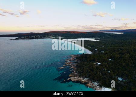 Ein weißer Sandstrand von Swimcart Beach bei Sonnenuntergang mit Binalong Bay im Hintergrund, Tasmanien Stockfoto