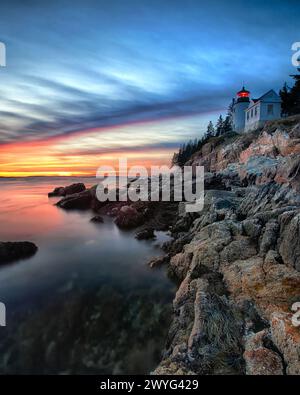 Vertikale Ansicht eines Leuchtturms auf einer Klippe bei Sonnenuntergang, Bass Harbor Head Lighthouse, Maine Stockfoto