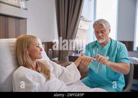 Der Arzt misst den Sauerstoffsättigungsgrad des Patienten während der Stationsrunde Stockfoto