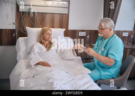 Der Arzt überprüft den Sauerstoffsättigungsgrad des Patienten während der Stationsrunde Stockfoto