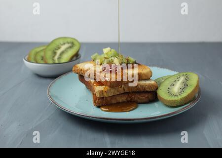 Honig auf Toast mit Früchten auf einem Teller auf grauem Hintergrund mit Platz für Text im Copyspace. Gesundes Frühstück. Stockfoto