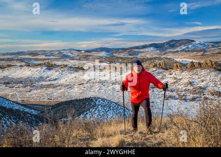 Senior männlicher Wanderer, der die Spitze eines Hügels in den Ausläufern der Rocky Mountains erreicht – Winterlandschaft im Devil's Backbone Open Space in der Nähe von Loveland, Colorado Stockfoto