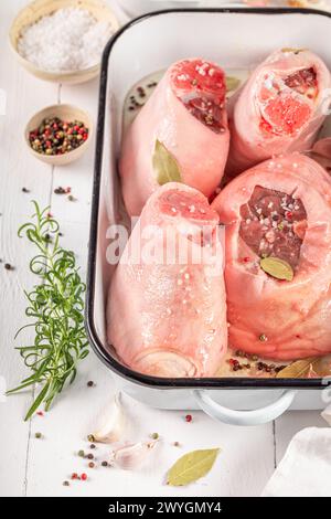 Zubereitung für gebratene Schweinshaxe, gebacken in einer hitzebeständigen Schale. Roher Schinken mit Gewürzen und Knoblauch. Stockfoto