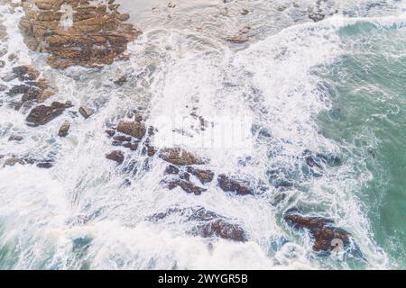 Blick von oben über die felsige Küste der Insel und das klare Meer mit wechselnden Blautönen und leichten schäumenden Wellen bei warmem Sommerwetter. Stockfoto