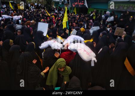 Kaschmirfrauen, die weißgehüllte Leichensäcke tragen, die Opfer im israelisch-palästinensischen Konflikt repräsentieren und während des "al-Quds"-Tages anti-israelische und -amerikanische Slogans singen, arabisch für Jerusalem, Kundgebung in Magam, indisch verwaltetes Kaschmir, Freitag, April 2024. Der Jerusalem-Tag begann nach der Islamischen Revolution im Iran 1979, als Ayatollah Khomeini den letzten Freitag des muslimischen heiligen Monats Ramadan zum Tag erklärte, um die Bedeutung Jerusalems für die Muslime zu demonstrieren. (Foto: Mubashir Hassan/Pacific Press) Stockfoto