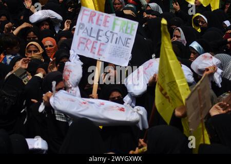 Kaschmirfrauen, die weißgehüllte Leichensäcke tragen, die Opfer im israelisch-palästinensischen Konflikt repräsentieren und während des "al-Quds"-Tages anti-israelische und -amerikanische Slogans singen, arabisch für Jerusalem, Kundgebung in Magam, indisch verwaltetes Kaschmir, Freitag, April 2024. Der Jerusalem-Tag begann nach der Islamischen Revolution im Iran 1979, als Ayatollah Khomeini den letzten Freitag des muslimischen heiligen Monats Ramadan zum Tag erklärte, um die Bedeutung Jerusalems für die Muslime zu demonstrieren. (Foto: Mubashir Hassan/Pacific Press) Stockfoto