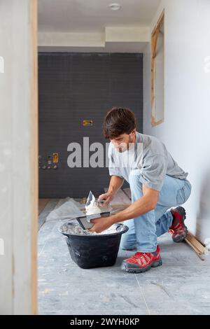 Maurer, der Fliesenkleber zum Fliesen aufträgt. Bau eines Wohngebäudes. Donostia. San Sebastian. Gipuzkoa. Baskenland. Spanien. Stockfoto