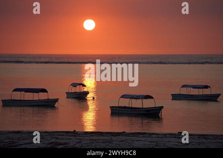 Vertäute Boote vor einem Strand in Sansibar bei Sonnenuntergang Stockfoto