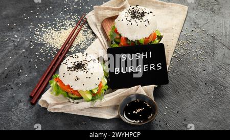 Asiatischer Sushi-Burger, Sojasauce, Essstäbchen auf dunklem Hintergrund. Trendiges Hybrid-Essen. Stockfoto