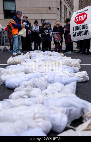 Demonstranten halten ein Banner mit der Aufschrift "die ganze Welt beobachtet" und "Juden sagen: Hör auf, Völkermord zu finanzieren" vor den auf dem Boden abgelegten Abbildungen. Eine kleine Gruppe von Demonstranten versammelte sich am Ende der Straße, in der Senator Chuck Schumer lebt, um ein sofortiges Ende aller US-Gelder für Israel zu fordern. Unter der Leitung der Aktivistengruppe Jewish Voice for Peace spaziert die Gruppe durch einen Bauernmarkt entlang des Prospect Park, auf dem Banner und Nachbildungen palästinensischer Kinder transportiert werden, die im Gaza-Streifen durch israelische Bombenangriffe im israelisch-Hamas-Krieg getötet wurden. Stockfoto