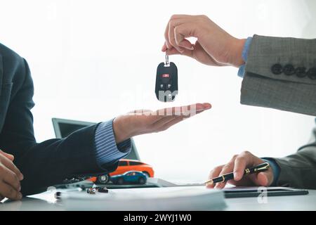 Der Autohändler übergibt dem Kunden Fahrzeugschlüssel, nachdem der Kaufvertrag und der Ratenzahlungsvertrag unterzeichnet wurden. Konzept der Übergabe von Autoschlüsseln an cu Stockfoto