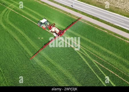 Themenfoto Landwirtschaft,Duengen,Pestizide, ein Landwirt faehrt mit seinenm Traktor ueber ein gruenes Feld und duengt mit Pestiziden. *** Themenfoto Landwirtschaft, Duengen, Pestizide, Ein Landwirt fährt seinen Traktor über ein grünes Feld und düngt mit Pestiziden Stockfoto