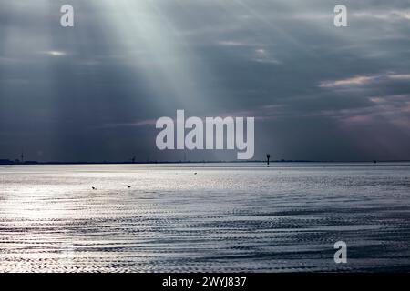 Sonnenuntergang mit Sonnenstrahlen und Sonnenspiegeln über dem Wattenmeer bei Otterndorf. Stockfoto