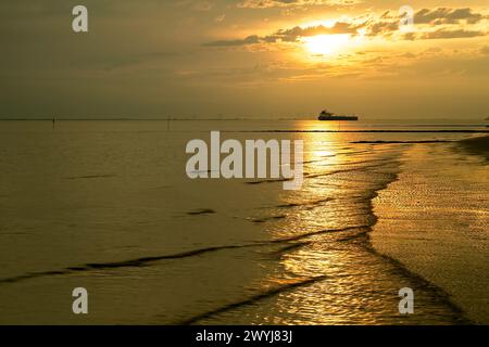 Sonnenaufgang über dem Wattenmeer bei Otterndorf, im Hintergrund ein Schiff in der Elbbahn. Stockfoto