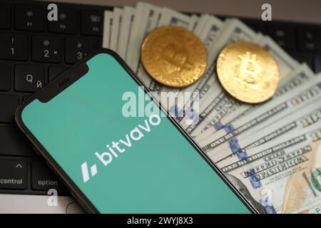 KIEW, UKRAINE - 15. MÄRZ 2024 Bitvavo-Logo auf dem iPhone-Display mit Dollars und Bitcoins auf dem MacBook. Portal für den Austausch von Kryptowährungen Stockfoto