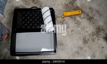 Werkzeuge zur Grundierung von verputzten Oberflächen für die weitere Lackierung. Malwalze in einem schwarzen Fach mit grauer Farbe. Walze mit Tablett und Farbe. Stockfoto