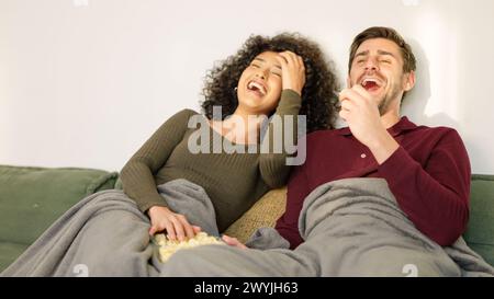 Ein Paar lacht, während er zu Hause einen lustigen Film ansieht Stockfoto