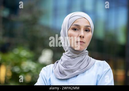 Eine moderne muslimische Frau im Hijab steht selbstbewusst in einer urbanen Umgebung und strahlt Ermächtigung und Vielfalt aus. Stockfoto