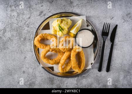 Gebratene Calamari mit Kartoffelsalat daneben auf Steintisch Stockfoto