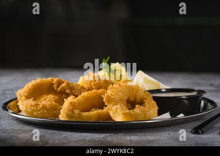 Gebratene Calamari mit Kartoffelsalat daneben auf Steintisch Stockfoto