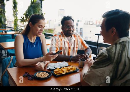 Lächelnde Gruppe von Freunden trifft sich im Café, um etwas zu trinken und zu reden Stockfoto