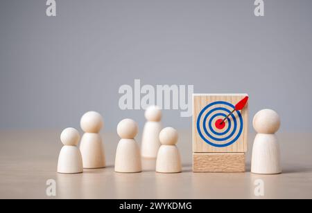Zielkonzept von Geschäft und Personal im Unternehmen. Holzpuppen stehen um Zielbrett und Pfeil. Erstellung und Ausrichtung von Geschäftszielen. Stockfoto