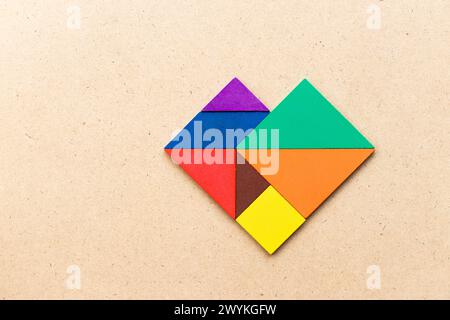 Farb-Tangram-Puzzle in Herzform auf Holztisch Stockfoto