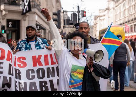 Eine Demonstrantin hält während des Marsches in London ihre Faust hoch. Die kongolesische Diaspora und ihre Verbündeten protestierten vor dem Londoner Hauptquartier Apple gegen die Gewalt und die Ausbeutung von Mineralien im östlichen Teil der Demokratischen Republik Kongo, wo die Kämpfe zwischen den kongolesischen Truppen und der ruandischen M23-Rebellengruppe stattfinden. Der Konflikt verursachte eine wachsende Flüchtlingskrise, Menschenrechtsverletzungen und billige Arbeitskräfte für den Bergbau. Alle Mineralien wie Coltan, Kobalt usw., die von Unternehmen wie Apple für Handys und Batterien verwendet werden. Stockfoto