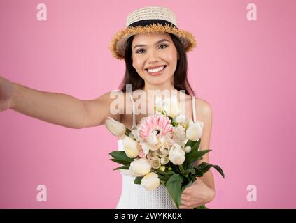 Frau, die Selfie mit Hut und Blumen macht Stockfoto