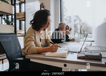 Erfolgreiches Team aus verschiedenen Mitarbeitern, die am Bürotisch an Geschäftsprojekten zusammenarbeiten. Stockfoto