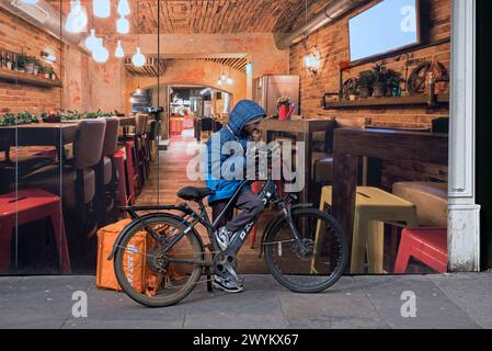 Lebensmittelzustellkurier Radfahrer überprüft sein Handy in der Princes Street, Edinburgh, Schottland, Großbritannien. Stockfoto