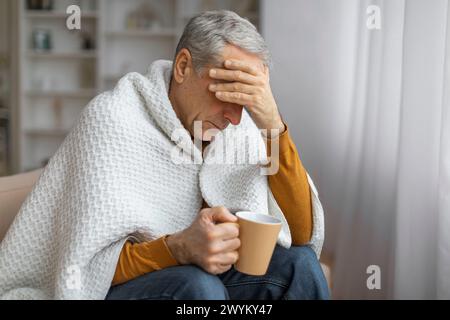 Ein älterer Mann hält einen Becher mit besorgtem Ausdruck Stockfoto