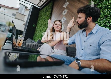Zwei junge Geschäftspartner diskutieren neue Projektpläne bei einem Kaffee in einer geschäftigen Coffee Bar im Stadtzentrum, umgeben von Herbstlaub. Stockfoto