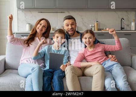 Glückliche Familie, die mit Tablet auf der Couch sitzt Stockfoto