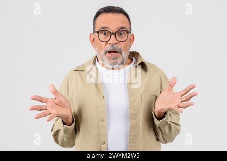 Überraschter hochrangiger bärtiger Mann mit offenen Händen Stockfoto