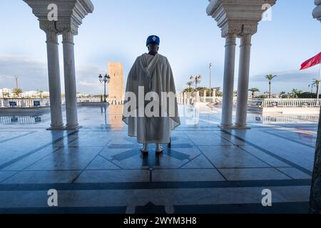 Ein marokkanischer königlicher Soldat bewacht den Eingang des Königlichen Mausoleums von Mohammed V. in Rabat, Marokko. Im Hintergrund befindet sich die alte Moschee von Sultan Stockfoto