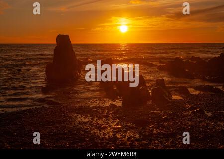 Ein feuriger Sonnenuntergang beendet einen angenehmen Sommertag an der Küste Cornwalls. Widemouth Bay, Cornwall Stockfoto